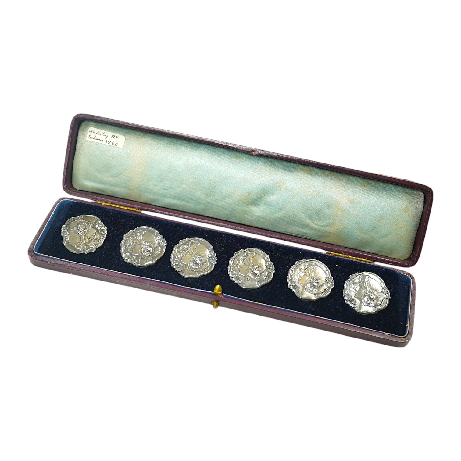 A cased set of six Edwardian Art Nouveau silver buttons, decorated with the head of a lady, import marks for Robert Friederich, London, 1902, 24mm. Condition - fair to good